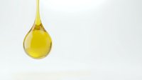 Golden oil drop falling from spoon against white background for cooking and culinary applications.
