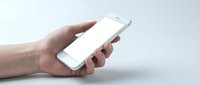 Male hand holding white smartphone with blank screen on light background for mockup and app presentation purposes.