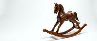 Vintage wooden rocking horse toy with ornate painted details and leather saddle on white background for nostalgic childhood memories and classic decor.