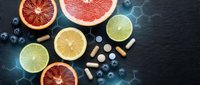 Fresh citrus fruits with vitamin supplements and blueberries on dark slate background for healthy lifestyle and nutrition concepts.