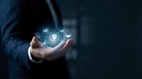 Businessman holding glowing digital technology icons in cupped hands representing innovation, connectivity and modern business solutions on dark background.