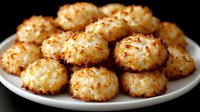 Golden coconut macaroons arranged on white plate against dark background. Sweet homemade cookies with toasted coconut flakes for dessert and baking projects.
