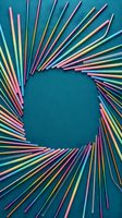 Colorful drinking straws arranged in circular pattern on turquoise background creating vibrant rainbow frame with copy space for text or design elements.