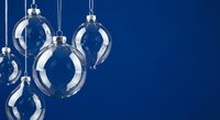 Elegant transparent glass Christmas ornaments hanging against deep blue background for holiday decorations and festive seasonal design projects.
