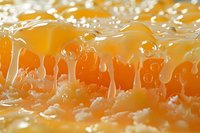 Dripping golden honey macro shot with detailed texture showing viscous liquid strands and air bubbles against bright orange background, natural food photography.