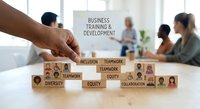 Hand placing wooden blocks with diversity and teamwork concepts while business professionals attend training session in modern office.