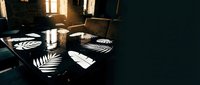 Elegant dining table set with striped plates and glassware, illuminated by warm sunlight casting dramatic shadows through windows for restaurant or hospitality design.