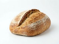 Artisan sourdough bread loaf with crispy crust and flour dusting, isolated on white background for bakery, food, and culinary design projects.