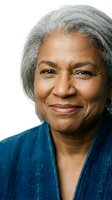 Portrait of confident mature African American woman with gray hair smiling warmly on white background for professional headshot and business content.