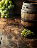 Rustic wooden wine barrel with fresh green grapes on dark wooden table, moody lighting creates dramatic atmosphere for wine and vineyard concepts.