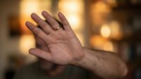 Adult male hand raised in stop gesture against warm blurred background with bokeh lights. Suitable for concepts of refusal, rejection, halt, warning, or defensive communication.