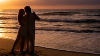 Romantic couple silhouette embracing on beach at golden sunset with ocean waves, love and intimacy concept for wedding anniversary Valentine's Day.