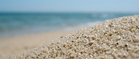 Sandy beach with shallow turquoise water and blurred horizon, suitable for travel, vacation, and summer holiday marketing materials.