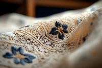 Delicate vintage lace fabric with embroidered blue flowers pattern, showing intricate crochet details and textile texture in soft natural lighting, macro photography.