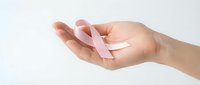Female hands gently holding pink ribbon symbol for breast cancer awareness campaign and women health support on clean white background.