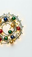 Colorful Christmas ornaments arranged in spiral pattern with warm LED string lights on white background for holiday decorations and festive designs.