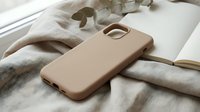Beige silicone phone case on linen fabric with eucalyptus branch and open book, minimalist lifestyle flat lay composition for mobile accessories.