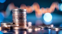 Stacked silver coins against blurred financial chart background with bokeh lights, representing investment growth and financial market analysis.
