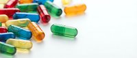 Colorful pharmaceutical capsules scattered on white background for medical and healthcare design projects.