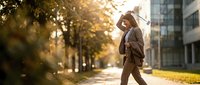 Professional businessman walking on urban street during golden hour sunset with warm lighting and autumn atmosphere in modern city environment.