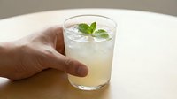 Fresh lemonade with mint garnish held in hand on white table, refreshing summer drink, cold beverage, natural ingredients, healthy lifestyle concept.