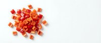 Fresh diced red bell pepper pieces scattered on white background, isolated vegetable ingredient for cooking and culinary preparations.