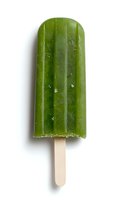 Green matcha popsicle on wooden stick isolated on white background, frozen dessert with frost texture showing refreshing summer treat.