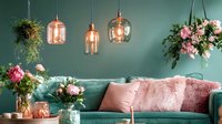 Modern living room interior with mint green wall, velvet sofa, rose gold pendant lights and pink floral arrangements creating cozy romantic atmosphere.