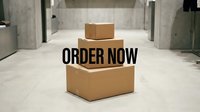 Stacked cardboard boxes with bold Order Now text, delivery and e-commerce concept on a minimalist concrete background.