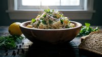 Potato salad with fresh herbs and vegetables served in rustic bowl, ideal for food blogs, recipe websites, cooking magazines, and culinary content creation.