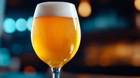 Glass of golden beer with white foam head against blurred bokeh background with warm and cool lights, suitable for beverage, bar, and hospitality marketing.
