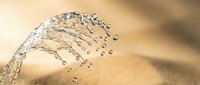 Water splash with droplets frozen in motion against warm golden background creating dynamic fluid movement and natural refreshing scene.
