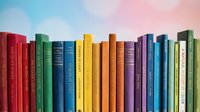Colorful row of vintage hardcover books with spines facing forward against soft pastel sky background, suitable for education, library, and publishing designs.