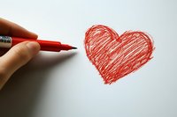 Hand holding red marker drawing heart shape on white paper, simple romantic doodle sketch showing love and affection. Creative Valentine concept for cards and designs.