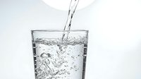 Clear water pouring into transparent glass with bubbles and splash creating refreshing drink concept for health and hydration lifestyle.