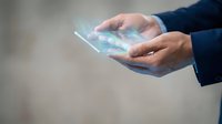 Male hands holding transparent digital tablet with holographic interface display, representing future technology and innovation.