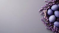 Purple painted Easter eggs decorated with dots nestled in artificial lavender flowers on gray background with copy space for seasonal holiday designs.