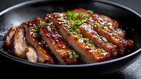 Juicy sliced duck breast with honey glaze sauce, garnished with sesame seeds and fresh chopped herbs served on black plate, close up view of gourmet meal.