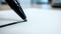 Black ink pen writing on white paper with shallow depth of field, suitable for business, education, and creative projects.