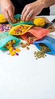 Male hands organizing colorful silicone food storage bags filled with diced mango, red onion, nuts, and seeds on wooden cutting board for meal prep and kitchen organization.