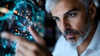 Mature businessman with gray beard examining futuristic holographic data visualization in blue neon light, wearing white shirt against dark background.
