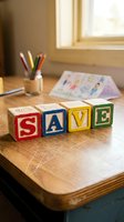 Colorful wooden alphabet blocks spelling SAVE on a rustic desk with pencils and children's drawings, symbolizing savings, education, and financial planning.