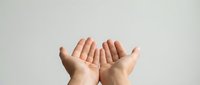 Open cupped hands gesture on neutral background showing palms up in receiving or offering position for charity, prayer, giving concepts.