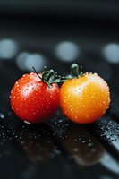 Fresh red and yellow cherry tomatoes with water droplets on dark background, macro photography with selective focus and bokeh effect for food blogs.