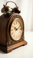 Vintage wooden alarm clock with dual brass bells, ornate carved details, and Roman numeral dial on white background for home decor and antique collections.