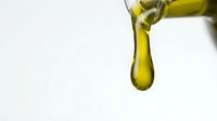 Olive oil dripping from bottle on white background, isolated for culinary, cooking, food packaging, and wellness design projects.