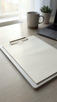 Minimalist workspace with blank clipboard, laptop, coffee mug and succulent plant on wooden desk near window for business planning and productivity.