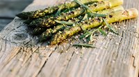 Grilled asparagus spears with herbs and seasoning on rustic wooden cutting board, healthy vegetable side dish for spring dining and cooking recipes.