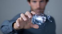 Businessman holding futuristic digital sphere with glowing blue technology interface, representing innovation and virtual data management.