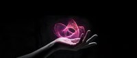 Hand holding glowing pink neon atom symbol against dark background, representing science, technology, innovation, and atomic energy for educational and futuristic design projects.